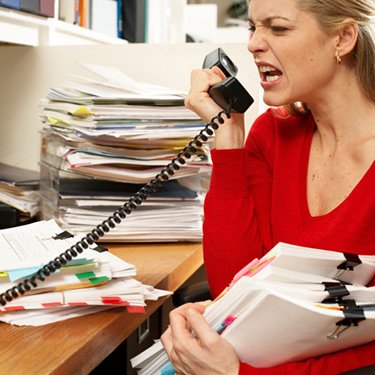 female-office-worker-holding-paperwork-and-snarling-into-phone_web