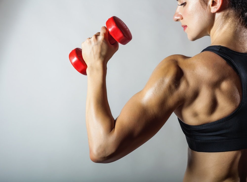 Fitness woman with barbells on grey background