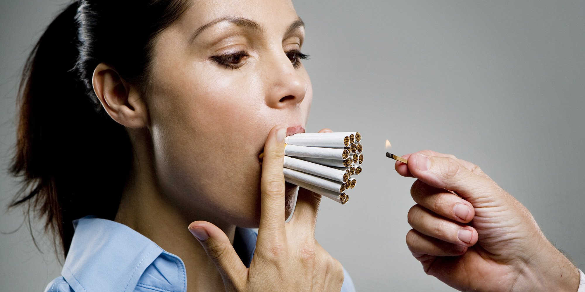 Woman with multiple cigarettes in mouth, man holding match