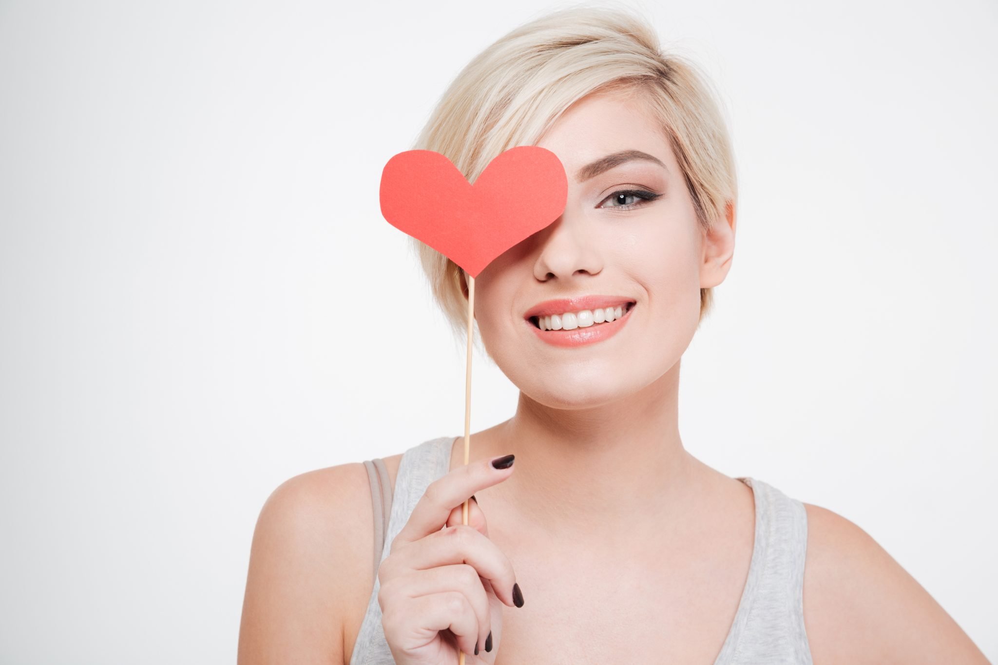 Smiling woman holding red heart isolated on a white background