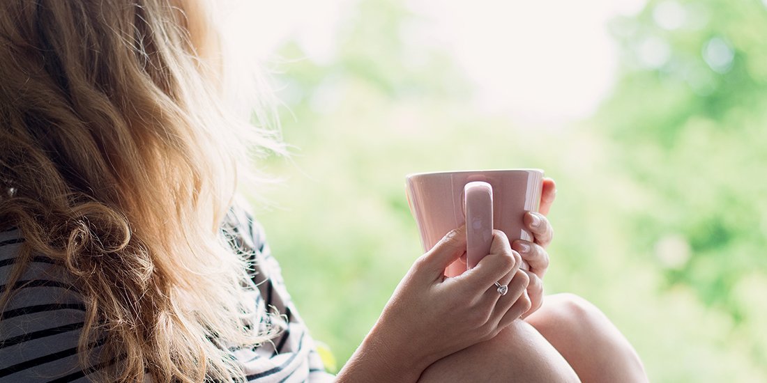 Peaceful woman relaxing at home with cup of tea or coffee